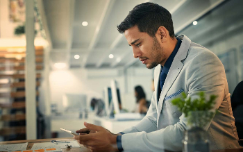 A business man looks at his cellphone in the office while.
